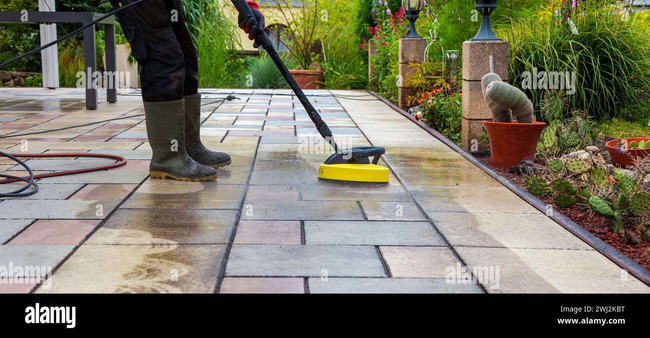 Cleaning stone slabs on patio with the highpressure cleaner. Person