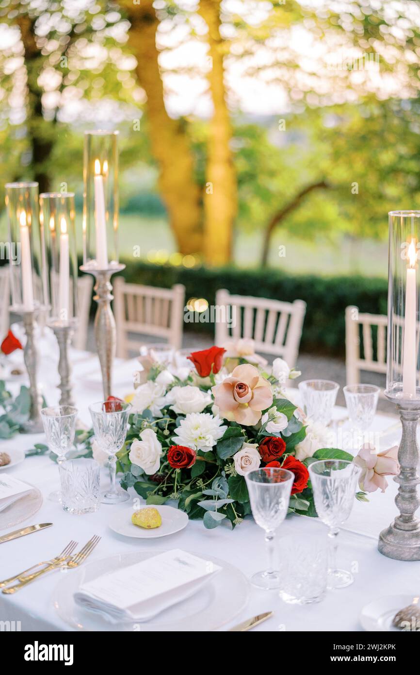 Colorful bouquet of flowers stands on a festive table near lit candles Stock Photo