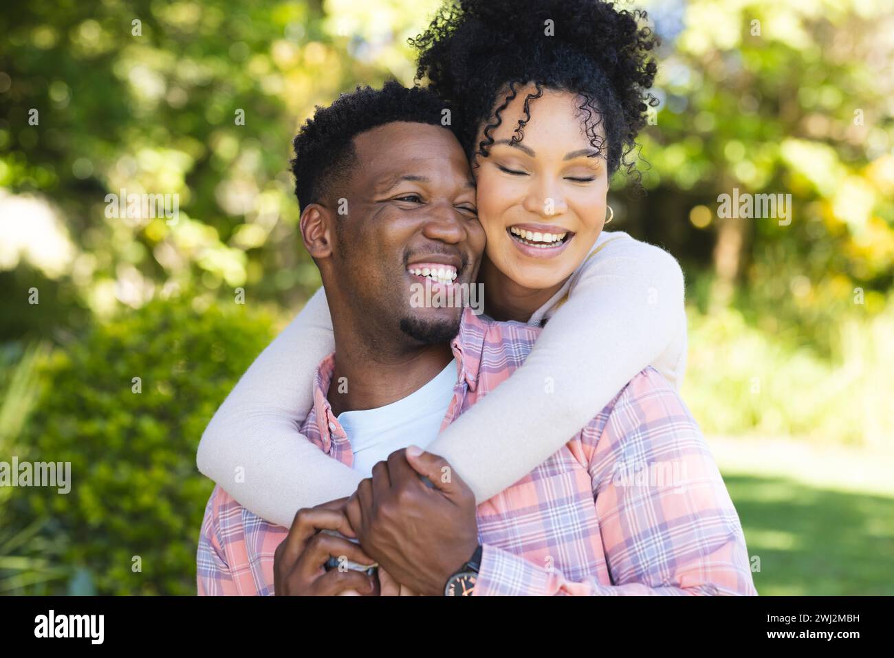 Happy african american couple embracing in sunny garden, copy space ...