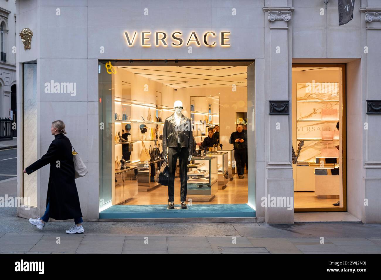 Street scene as people pass by the Versace store on Bond Street which has seen a recent drop in demand for luxury goods and with some stores deciding to move out on 4th February 2024 in London, United Kingdom. Bond Street is one of the principal streets in the West End shopping district and is very upmarket and has been a fashionable shopping street since the 18th century. The rich and wealthy shop here mostly for high end fashion and jewellery. Stock Photo