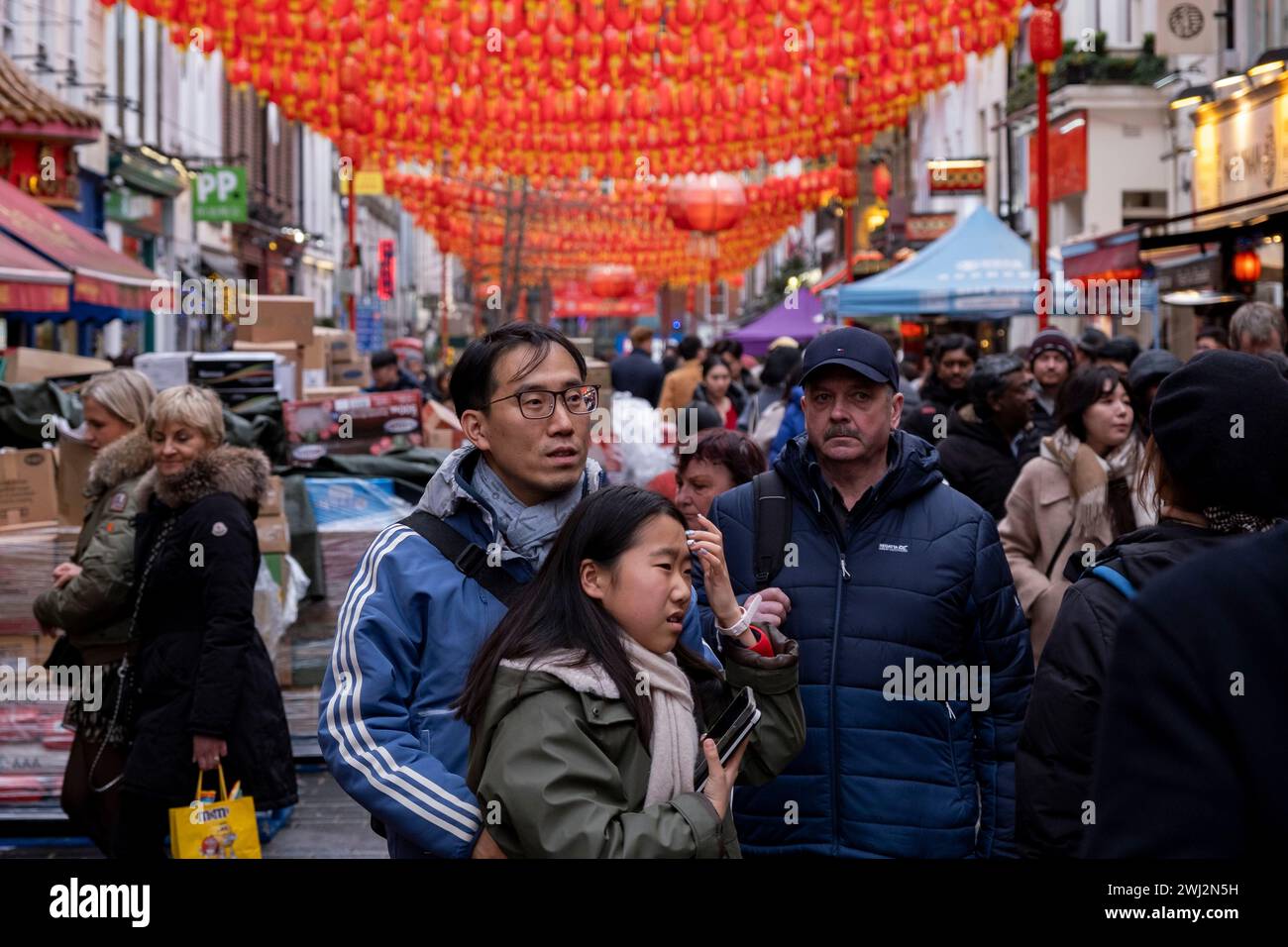 Street scene on Gerrard Street in Chinatown as newly installed red lanterns hang above in preparation for the Chinese Lunar New Year celebrations on 9th February 2024 in London, United Kingdom. Chinatown is an ethnic enclave bordering Soho and currently occupies the area in and around Gerrard Street. It contains a number of Chinese restaurants, bakeries, supermarkets, souvenir shops, and other Chinese-run businesses. Stock Photo