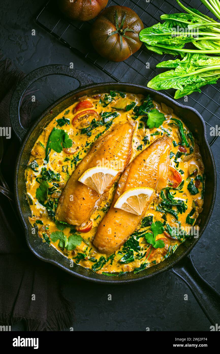 Red curry with spinach, coconut milk and baked fish in a pan Stock Photo