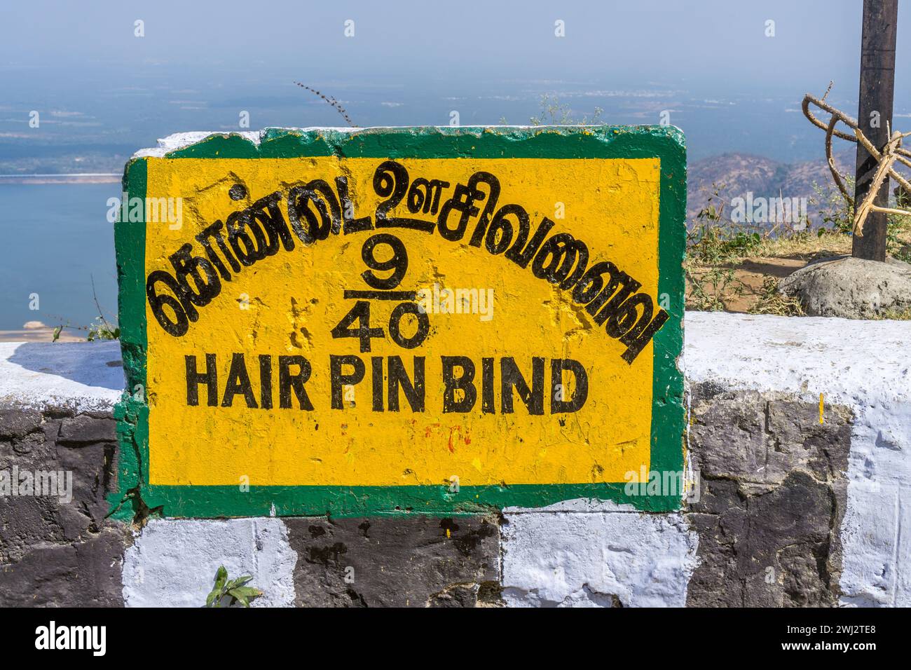 A sign indicating the 9th hair pin bend on the road from Pollachi to Valparai with the Aliyar reservoir on the background. Stock Photo