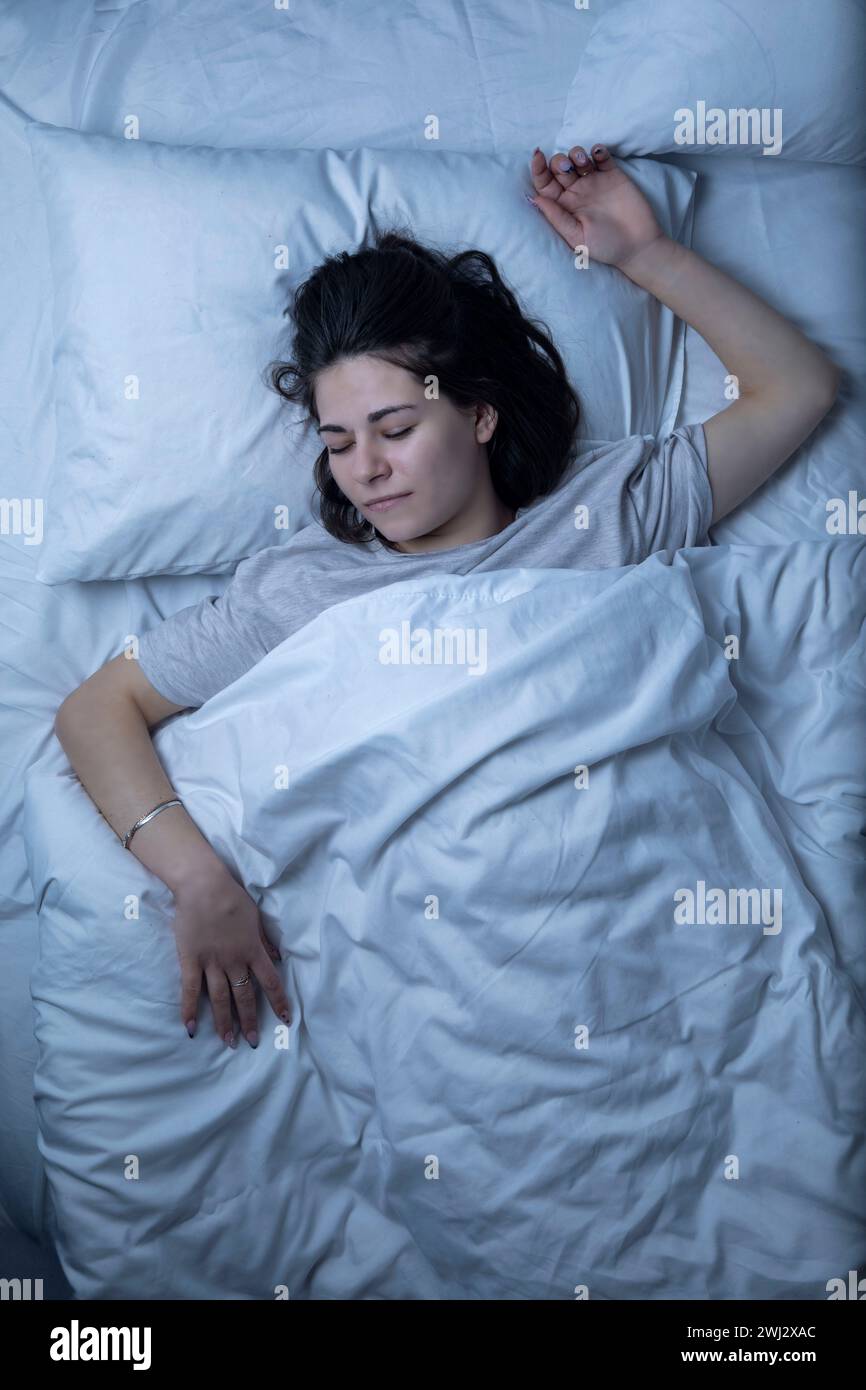 A beautiful girl is sleeping in a bed with a white sheet Stock Photo ...