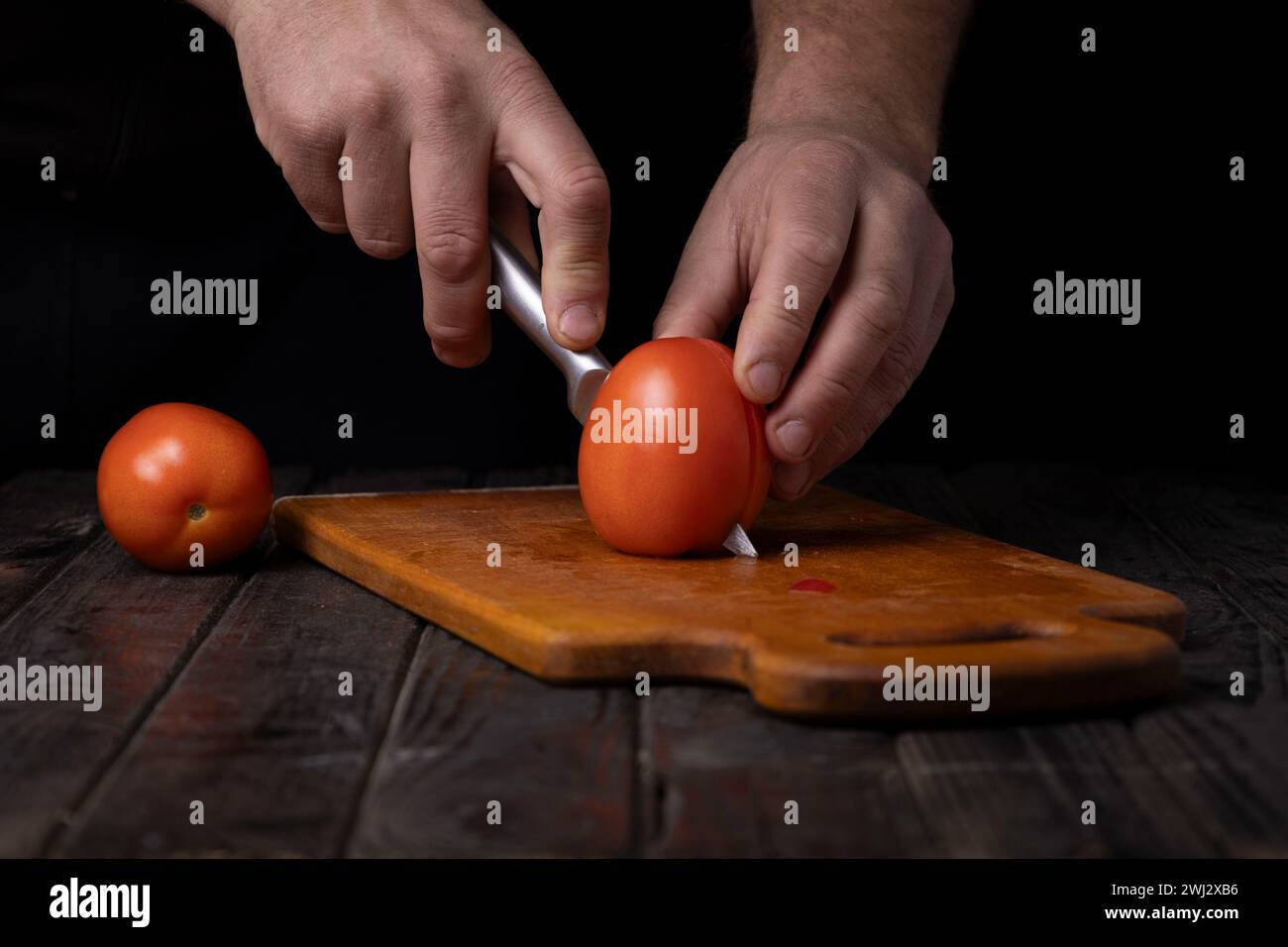 Cutting vegetables. Male hands cutting tomatoes on a cutting board Stock Photo