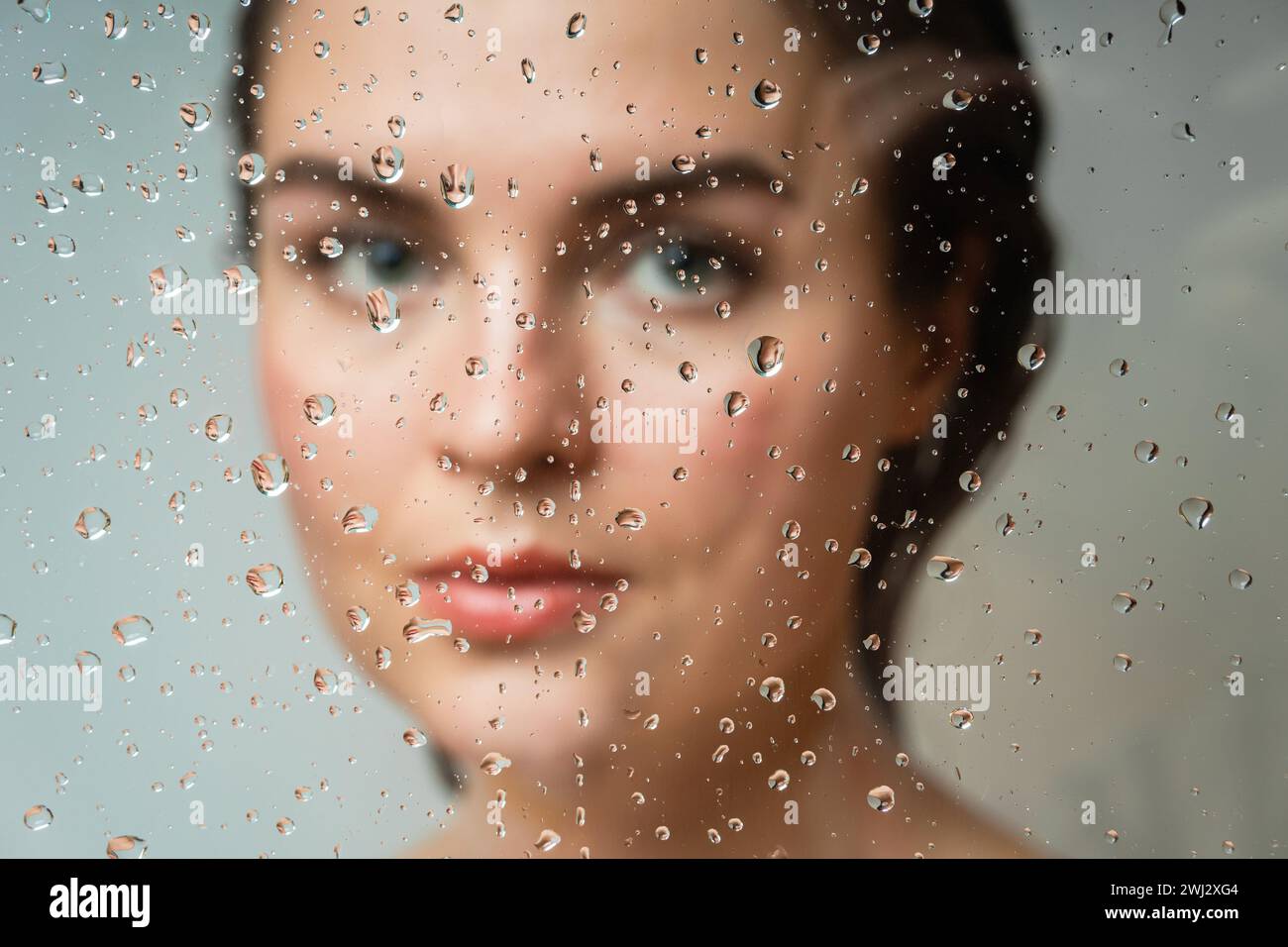 Woman behind the wet glass. Focus on the droplets Stock Photo Alamy