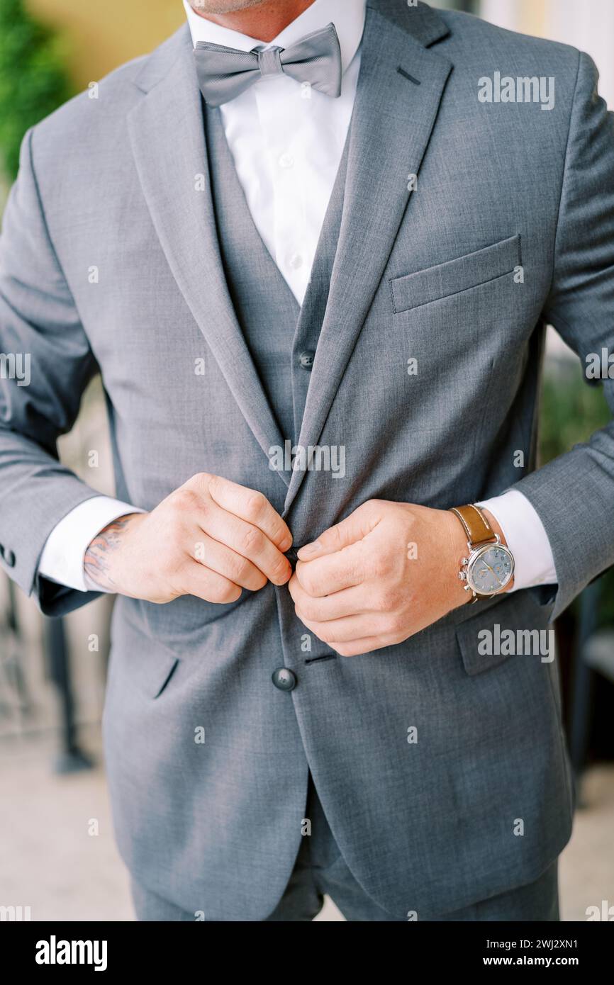 Groom fastens the buttons of his jacket. Cropped. Faceless Stock Photo