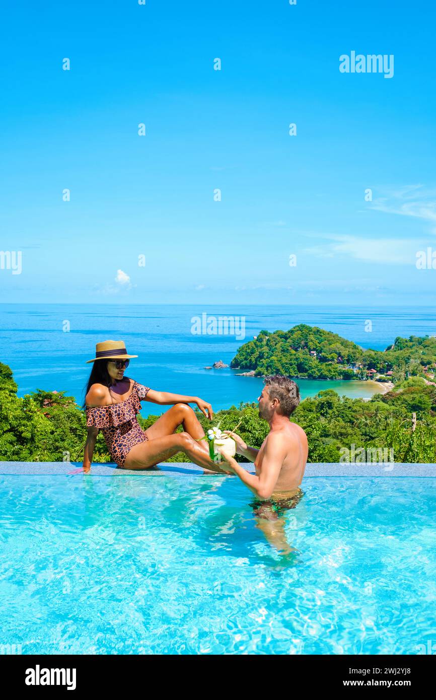 Young couple men and women at the swimming pool during vacation at the tropical islandscouple man and woman in infinity pool dur Stock Photo