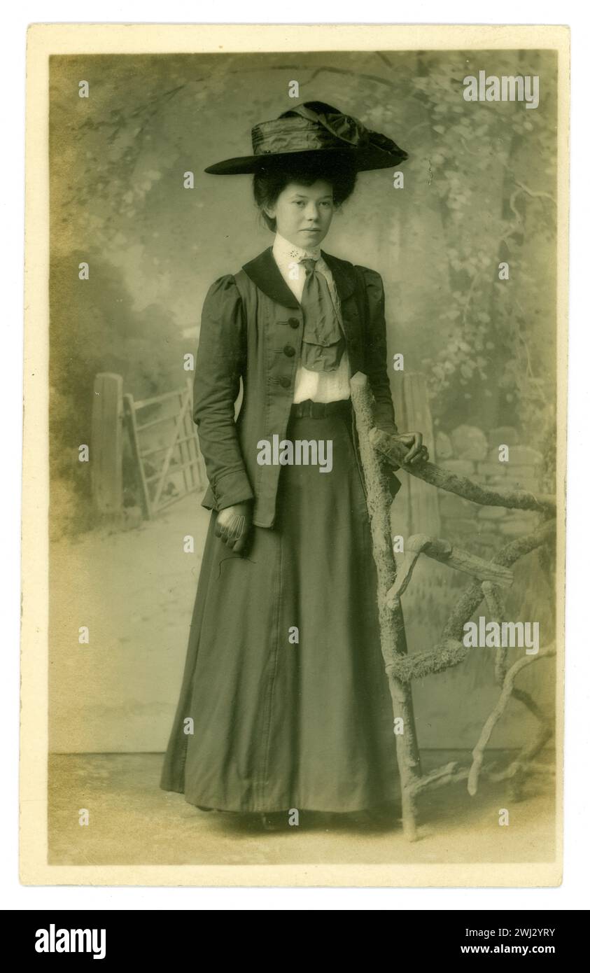 Original Edwardian era postcard of attractive lady, called Nellie. who appears to be a feminist, (from the back of the postcard) wearing a large hat., very typical of this era. She wears a long skirt with a long jacket over it. circa1909, U.K. Stock Photo