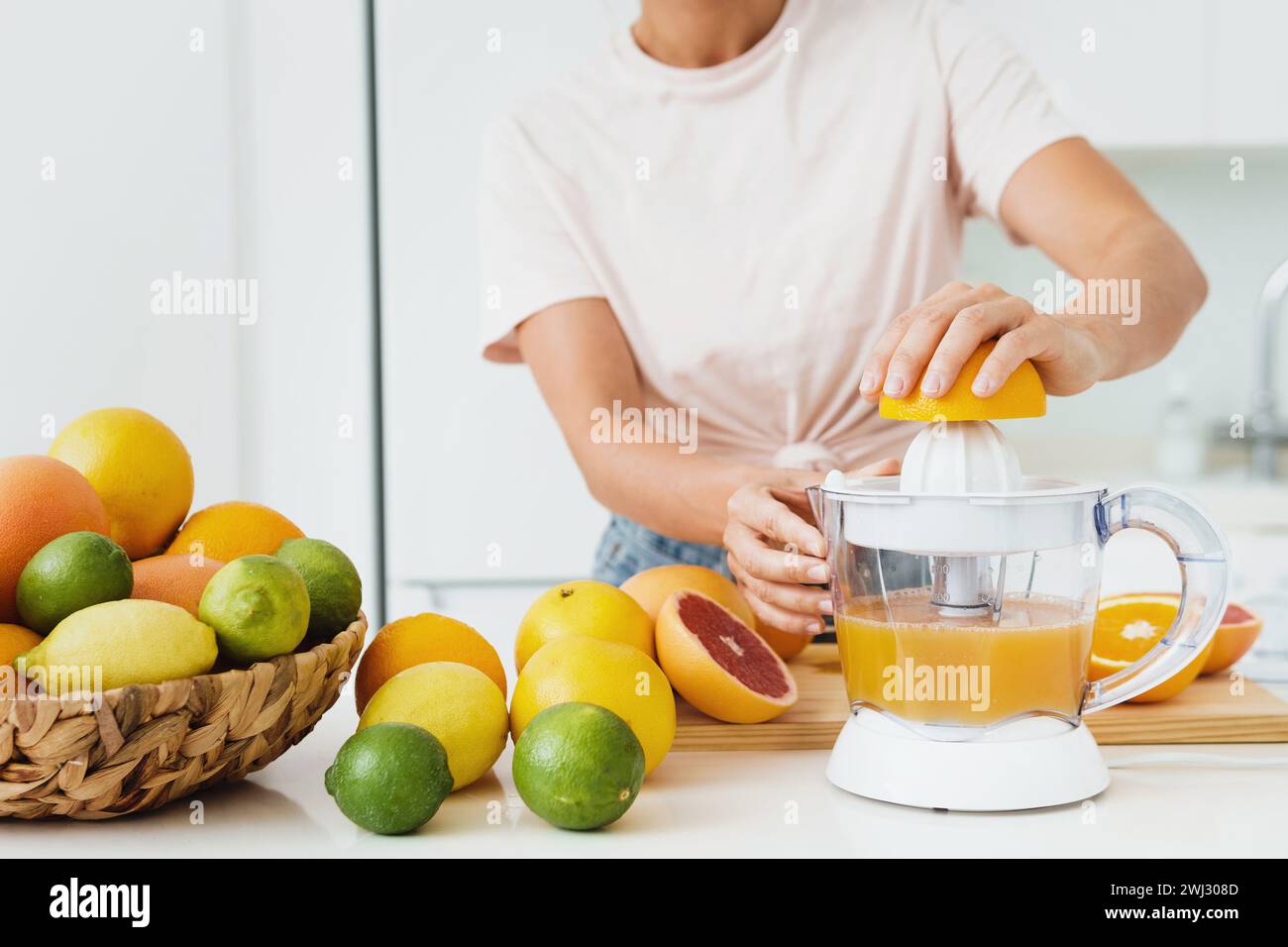Female hands and citrus juicer during fresh orange juice preparation Stock Photo