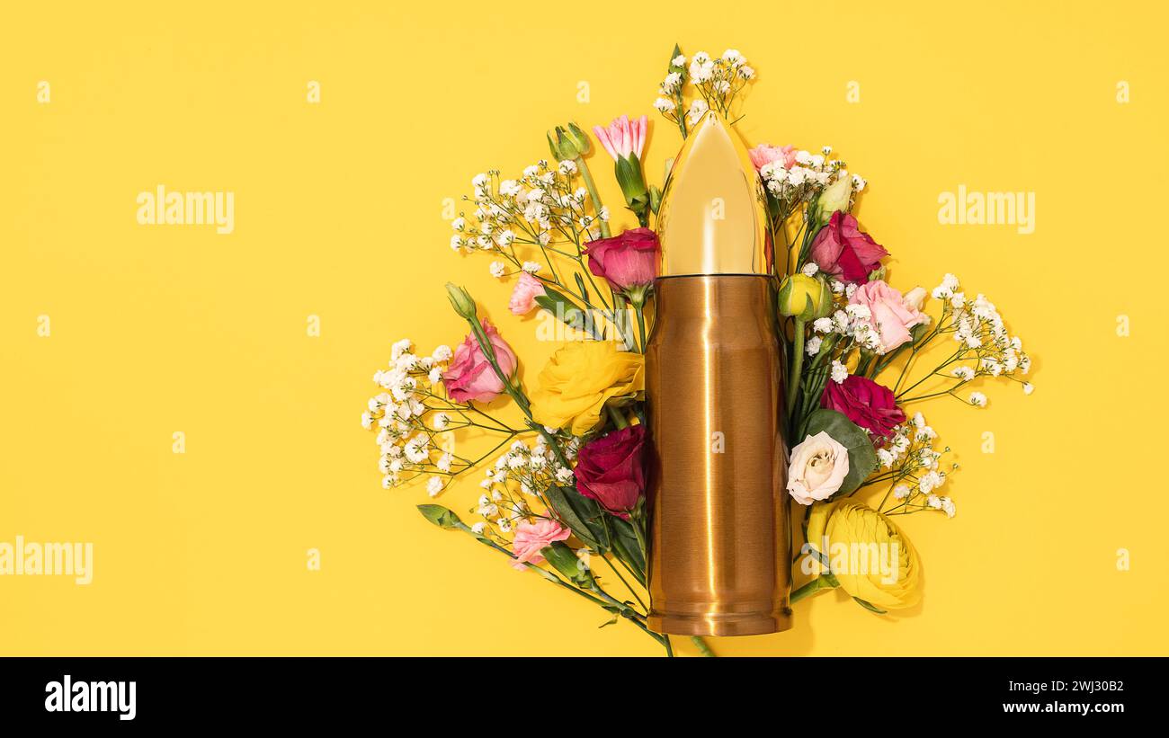 Pacifism and non-violence movement. Bullet and bunch of different flowers against yellow background. Stock Photo