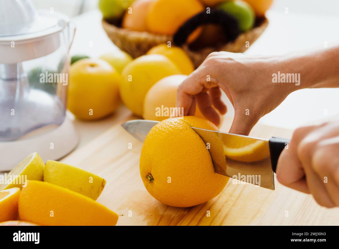 Female hands with knife cutting orange fruit for homemade fresh juice
