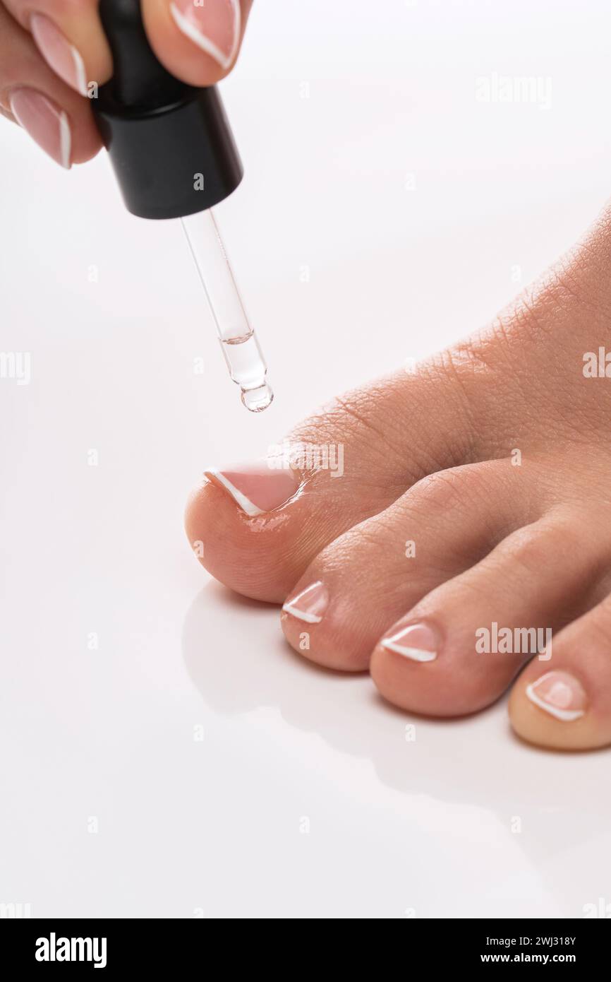 Closeup of female foot and bottle of nourishing cuticle oil with dropper Stock Photo