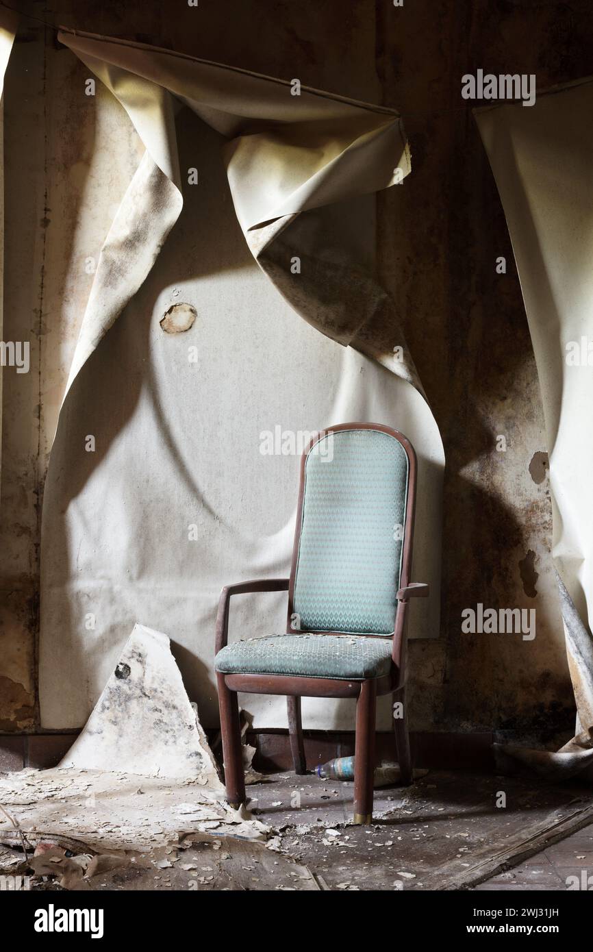 A lonely chair in a hallway with peeling wallpaper inside the Royal Connaught Hotel before renovations in Hamilton, Ontario, Canada Stock Photo