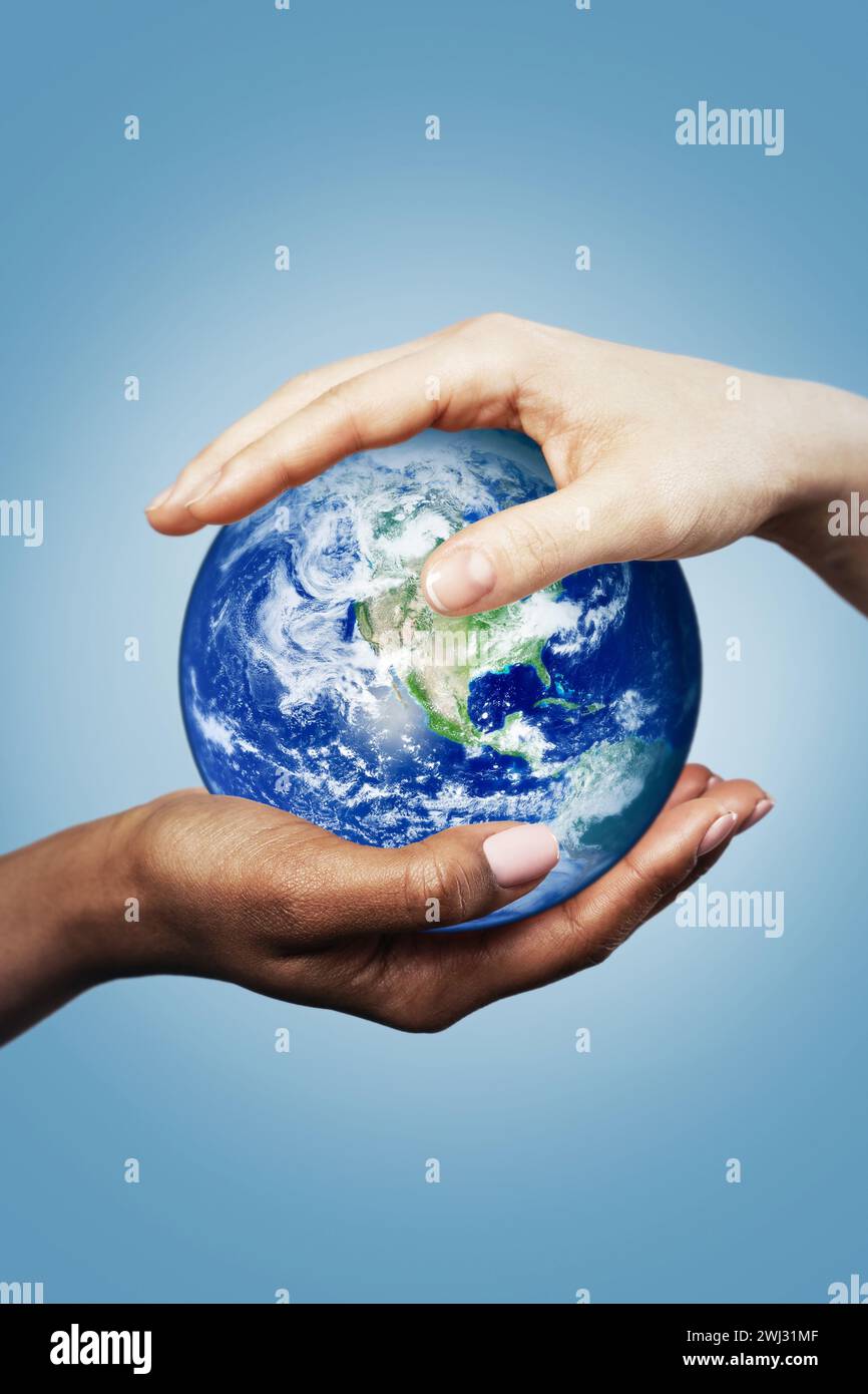 African and Caucasian female hands holding earth globe. Elements of this image furnished by NASA. Stock Photo