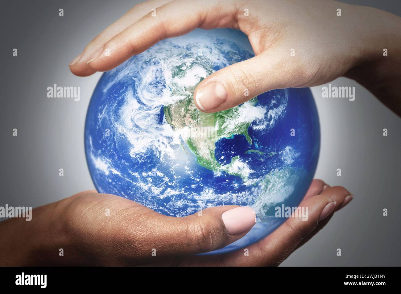 African and Caucasian female hands holding earth globe. Elements of this image furnished by NASA. Stock Photo