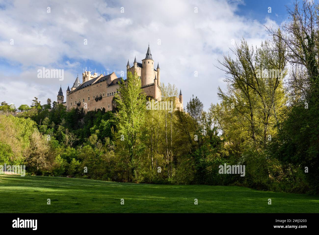 Photograph of the impressive castle of Segovia from the gardens on a day of blue sky and clouds, Spain Stock Photo