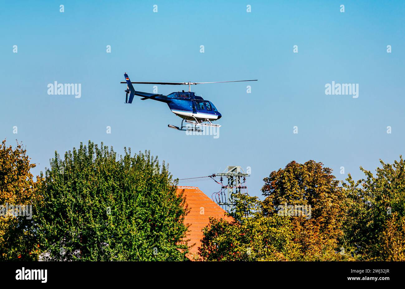 Helicopter flying in the sky. High voltage repair helicopter over residential building near a high Stock Photo