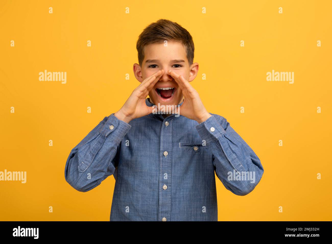 Excited teen boy cupping hands around mouth to shout an announcement Stock Photo