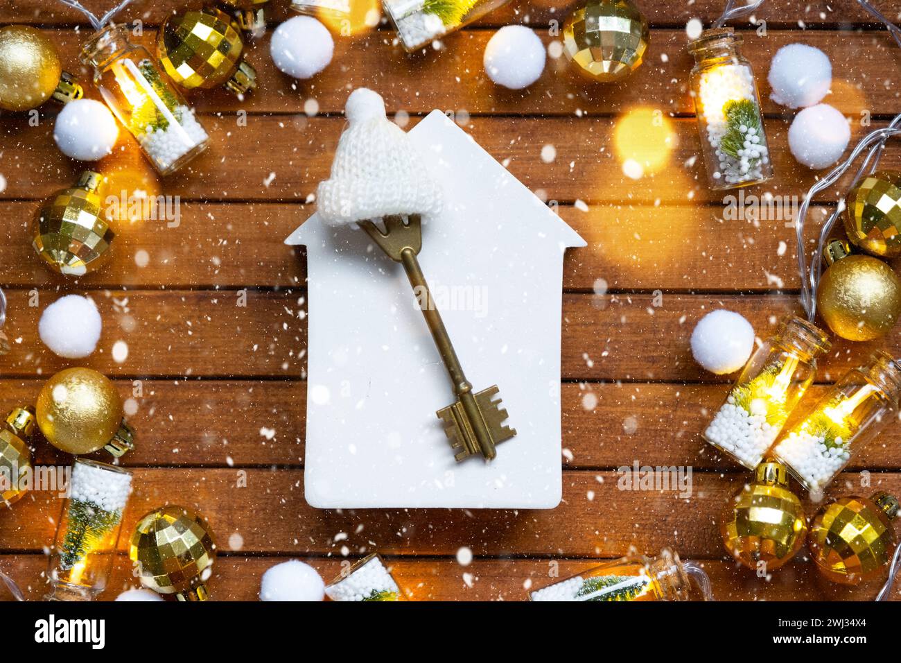 Key to house with a keychain tiny home on wooden background with Christmas decor layout. Gift for New Year, Christmas. Building, Stock Photo