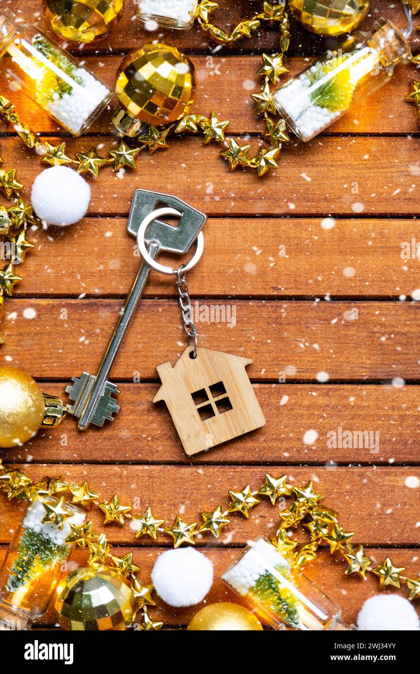 Key to house with a keychain tiny home on wooden background with Christmas decor layout. Gift for New Year, Christmas. Building, Stock Photo