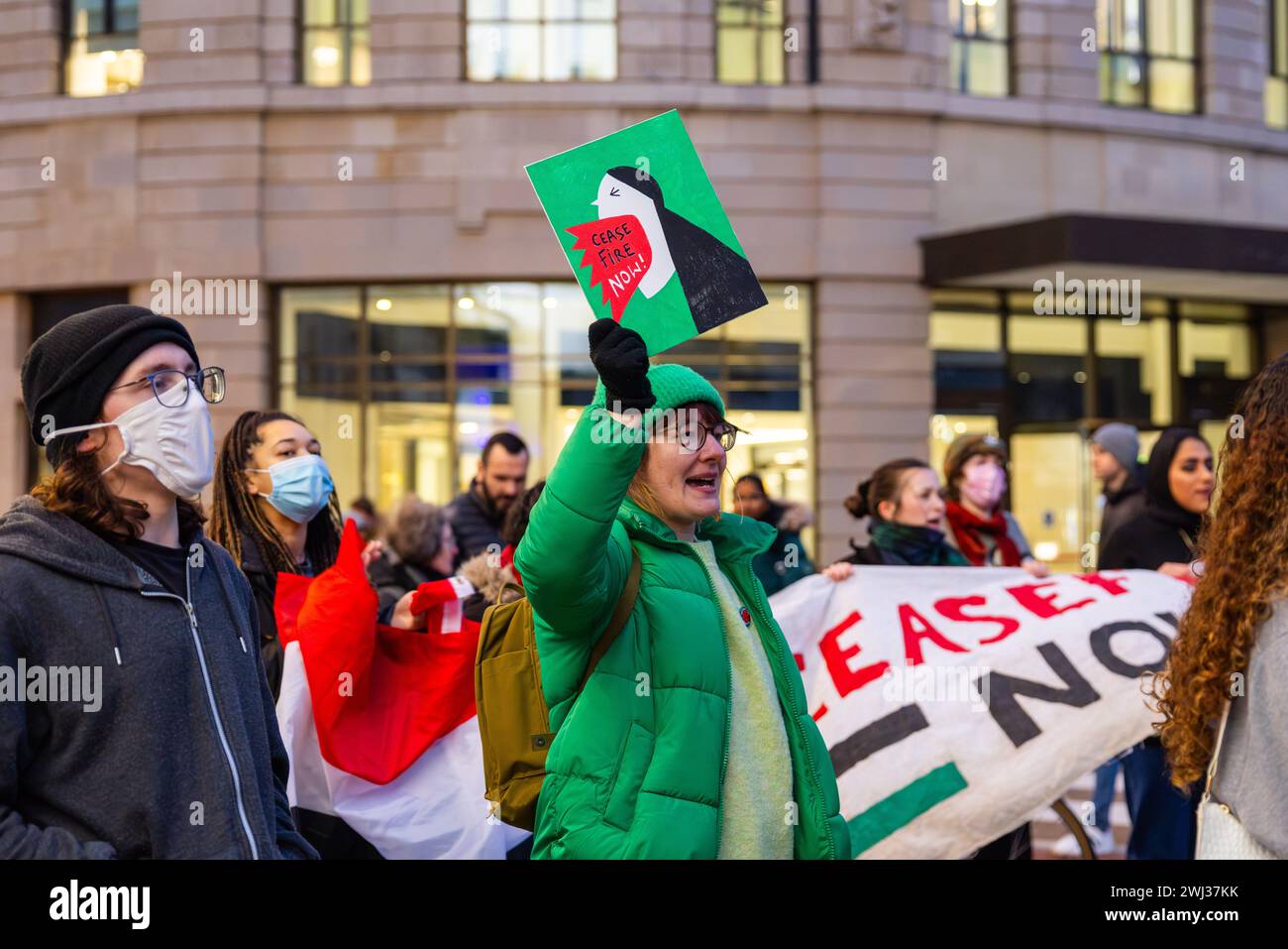 Leeds, UK. 12 FEB, 2024. Protestor holds a 'ceasefire now' placard  amongst other demonstrators gathered outside Leeds train station. Credit Milo Chandler/Alamy Live News Stock Photo