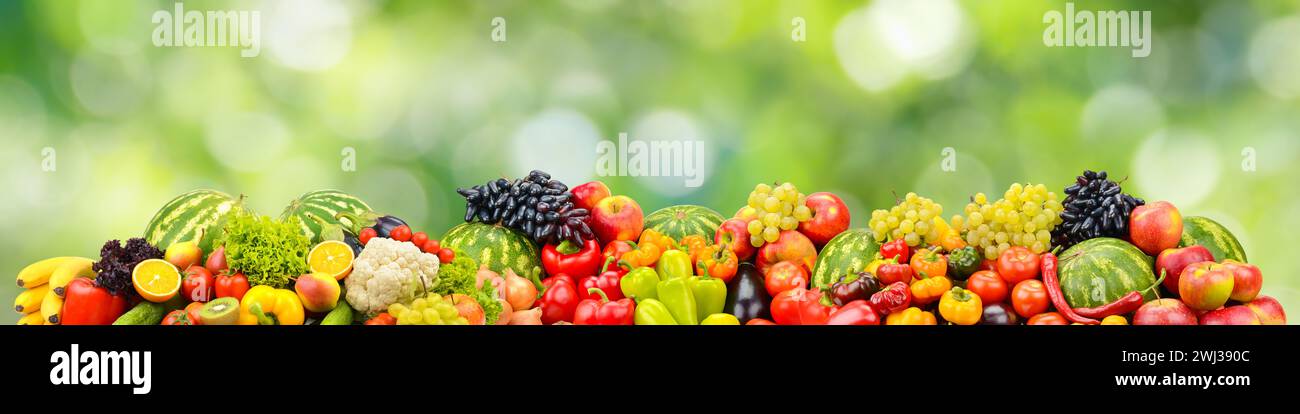 Fresh healthy vegetables, fruits, berries on green blurred background. Stock Photo