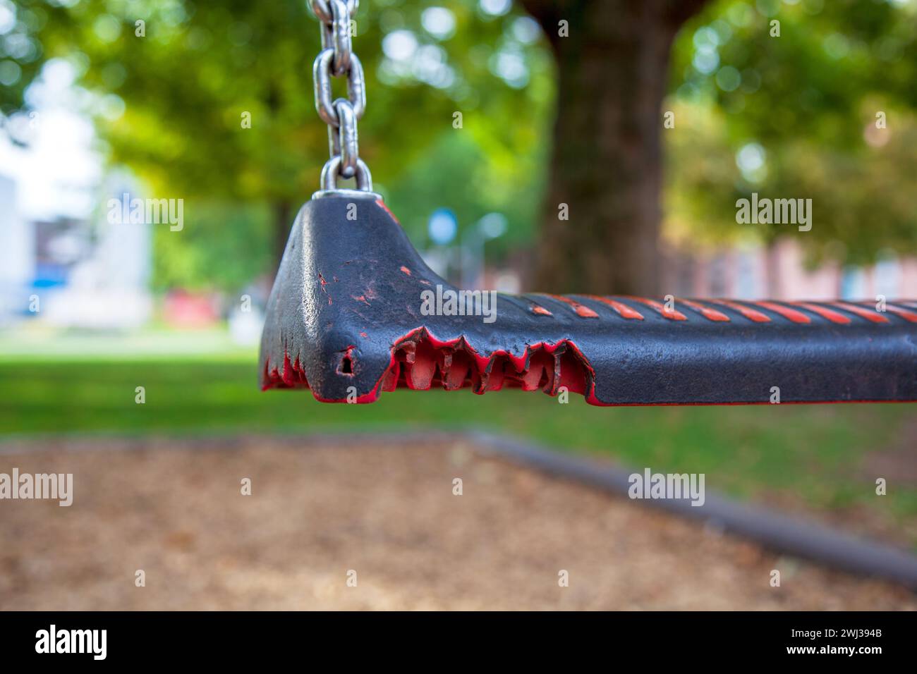 Broken equipment at playground. close-up of Empty swing in children playground. molten by fire. plas Stock Photo
