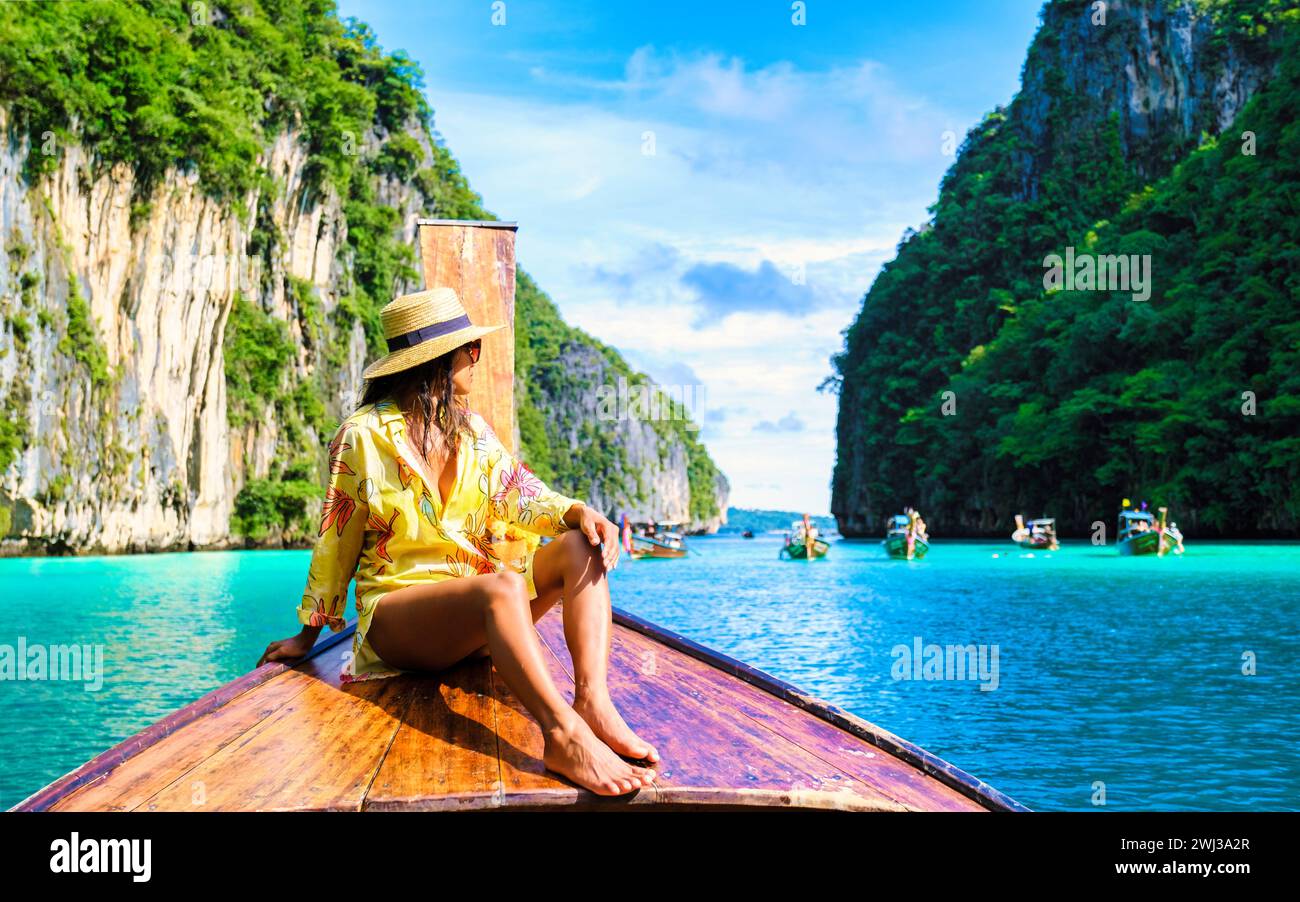 Asian women in front of a longtail boat at Kho Phi Phi Thailand at Pileh Lagoon with turqouse water Stock Photo