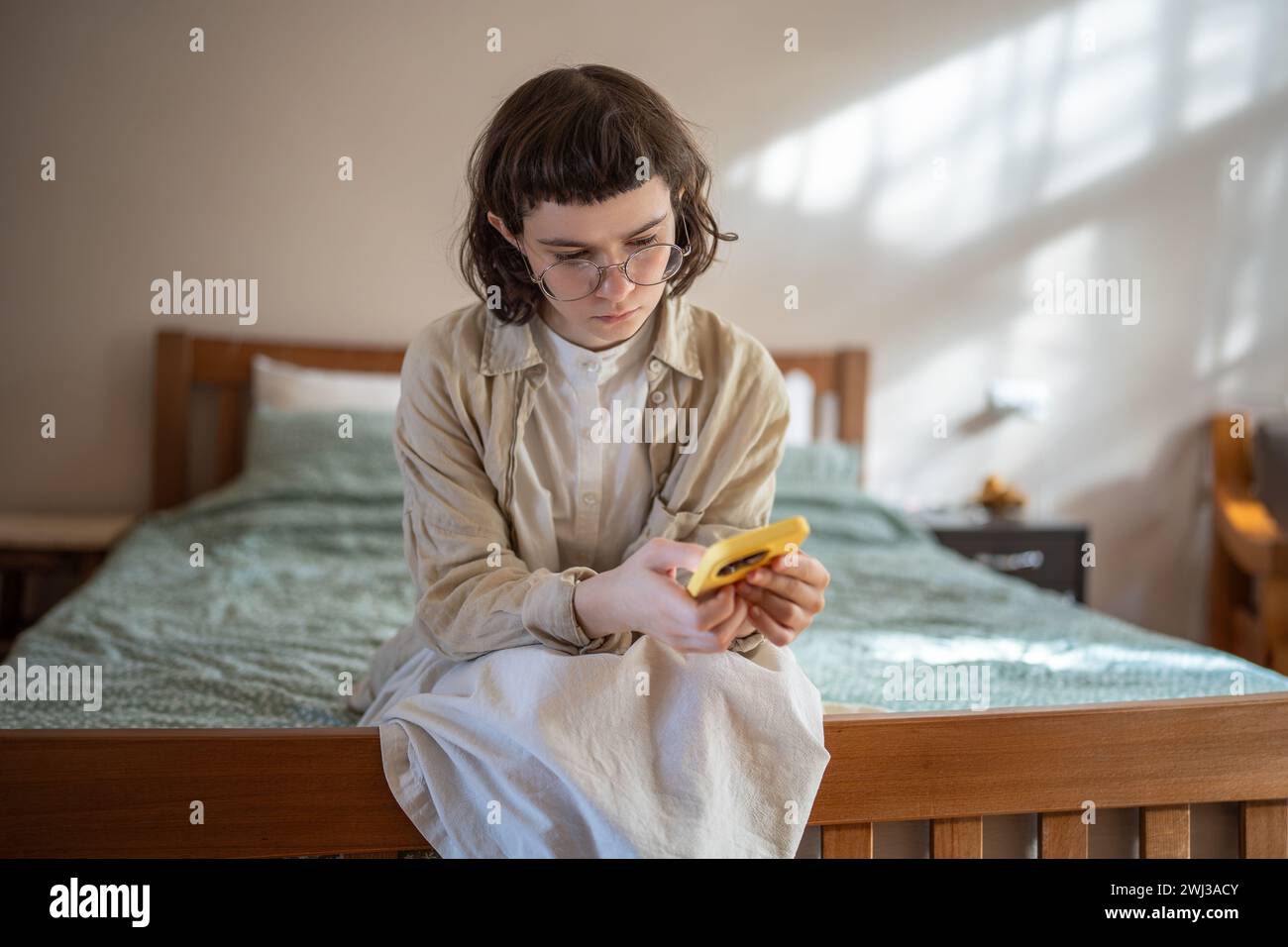 Outcast teenage girl obsessed with mobile phone, staying at home, feeling lonely, rejected, unhappy Stock Photo