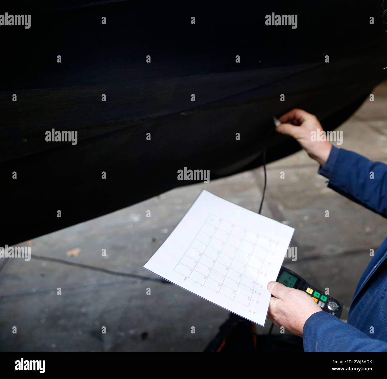 A service engineer measuring the thickness of the steel hull of a boat