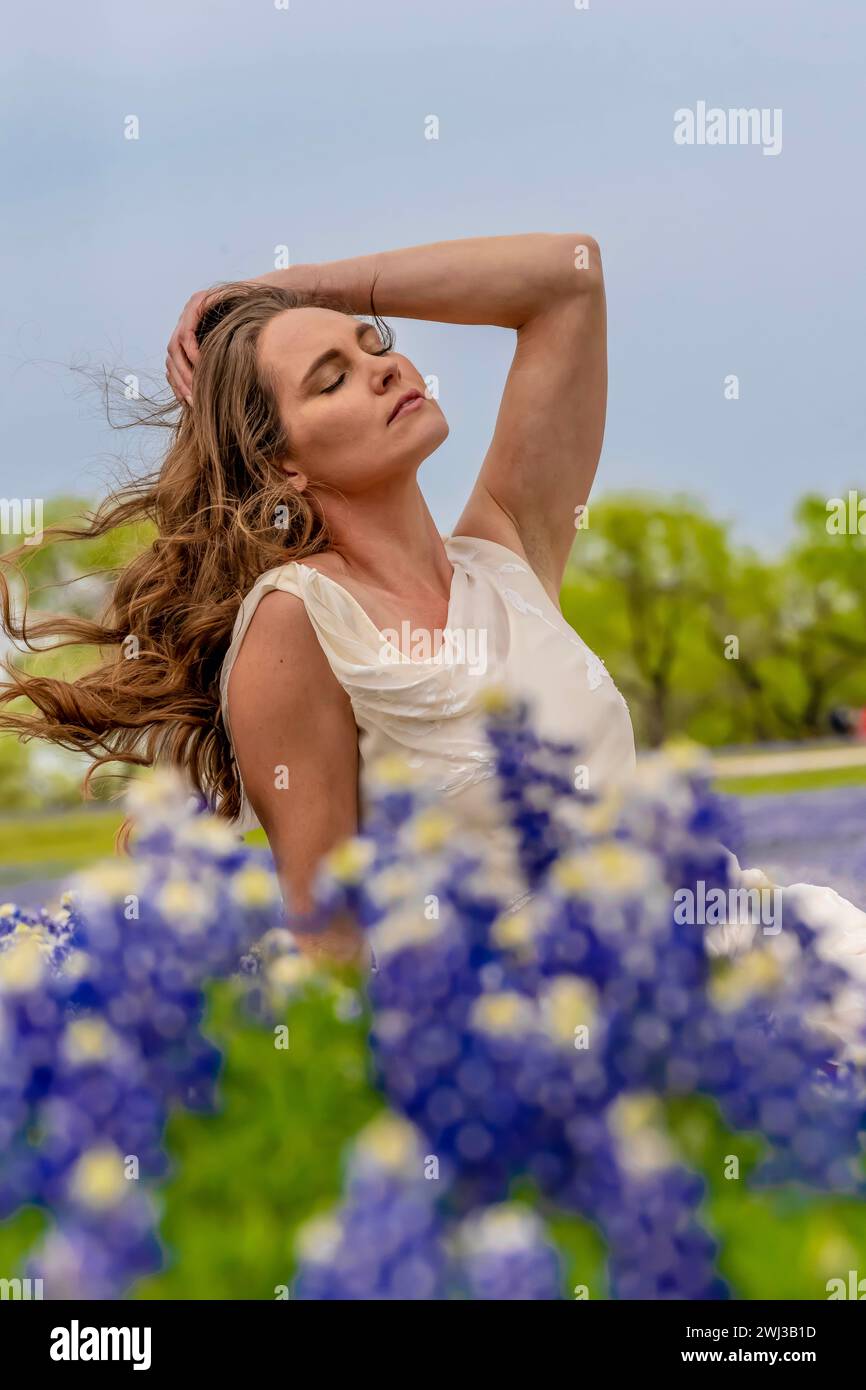 A Lovely Brunette Model Poses In A Field Of Bluebonnet Flowers In A Texas Prarie Stock Photo