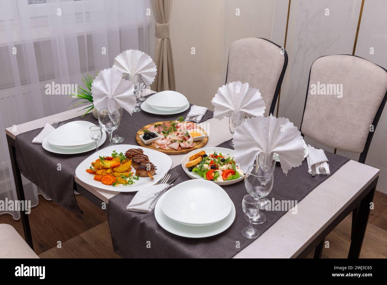 Table set up for four persons in a cafe, cafeteria, restaurant. Table and four chairs stand in corner of room. Empty seats for visitors. A place for a Stock Photo