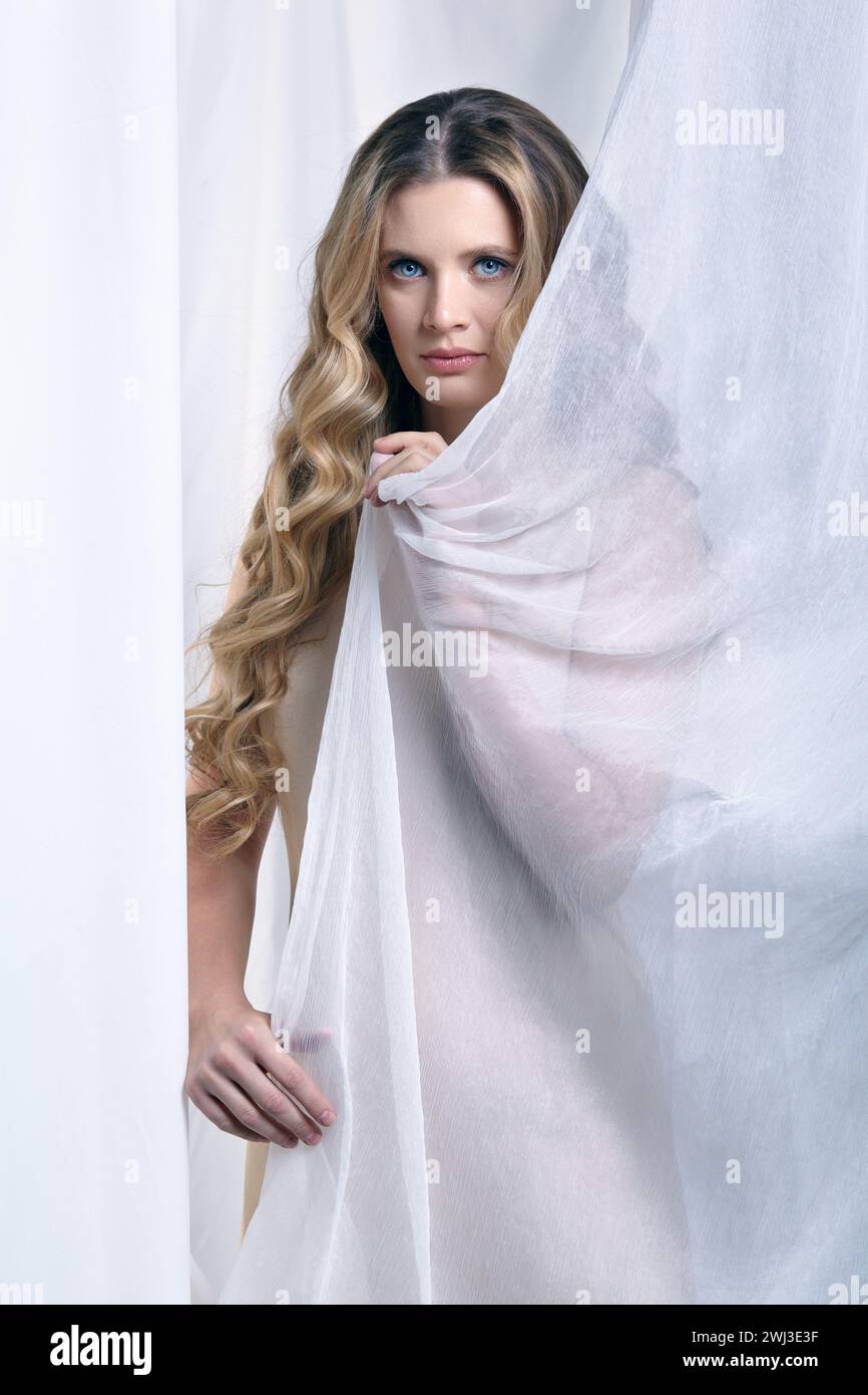 Portrait of a young woman against a background of white fabric. Female beauty concept. Stock Photo