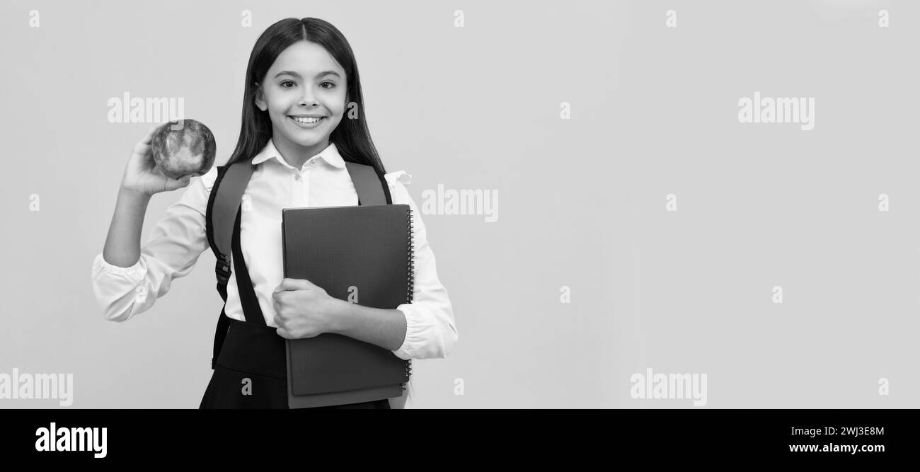 Happy kid go back to school holding apple and books yellow background, knowledge day. Portrait
