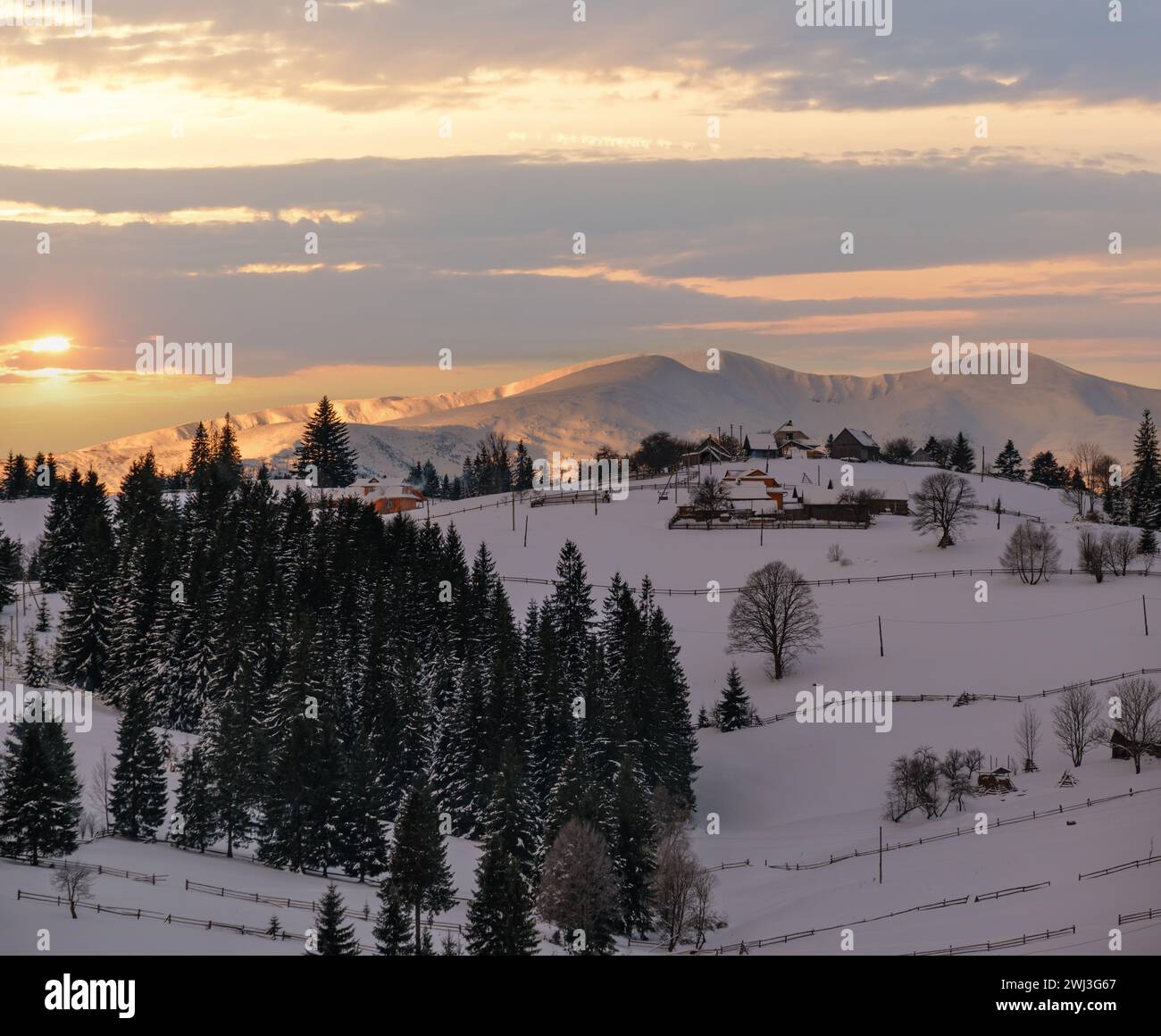 Small alpine village and winter snowy mountains in first sunrise sunlight around, Voronenko, Carpathian, Ukraine. Stock Photo
