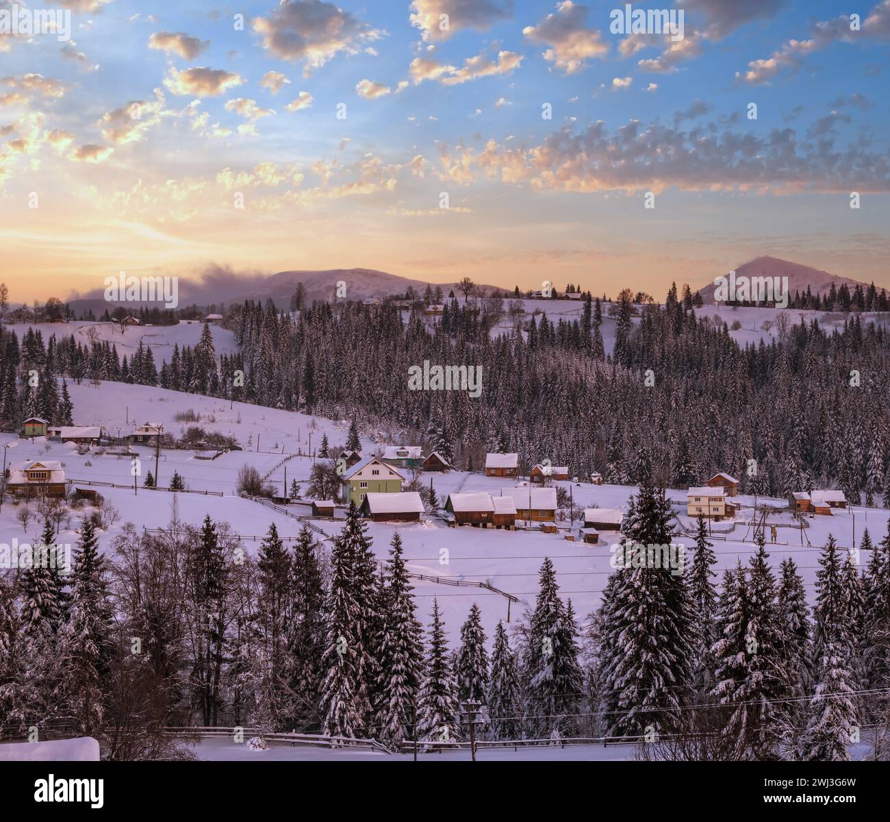 Pre-dawn alpine small quiet village and winter snowy mountains around Stock Photo