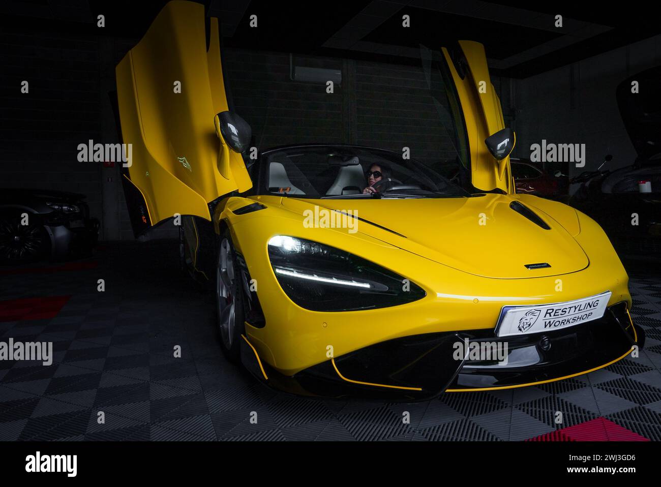 Yellow McLaren 765LT, featuring Dihedral Doors, parked in a Tuning Garage. Stock Photo