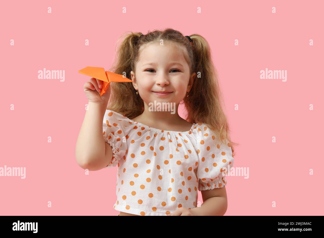 Cute little girl with paper plane on pink background Stock Photo - Alamy