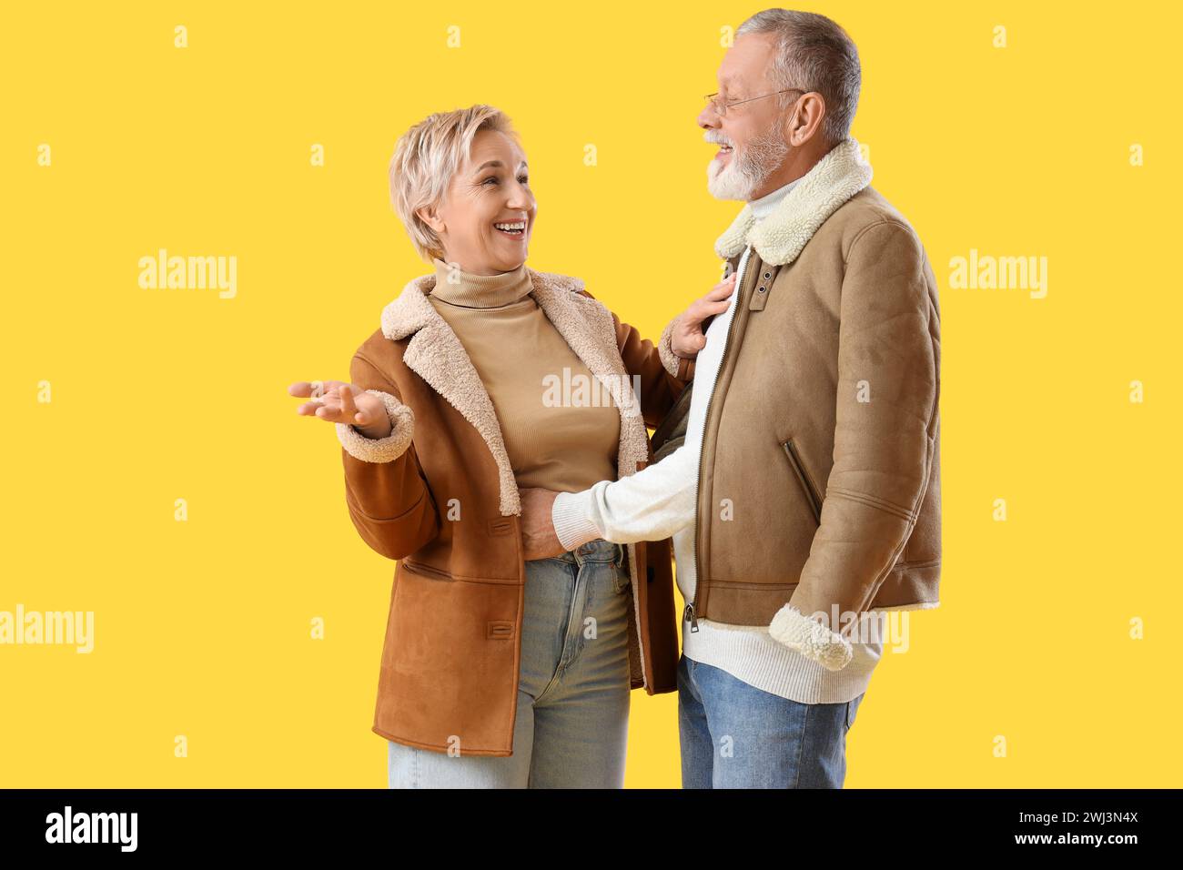 Mature couple in sheepskin coats on yellow background Stock Photo