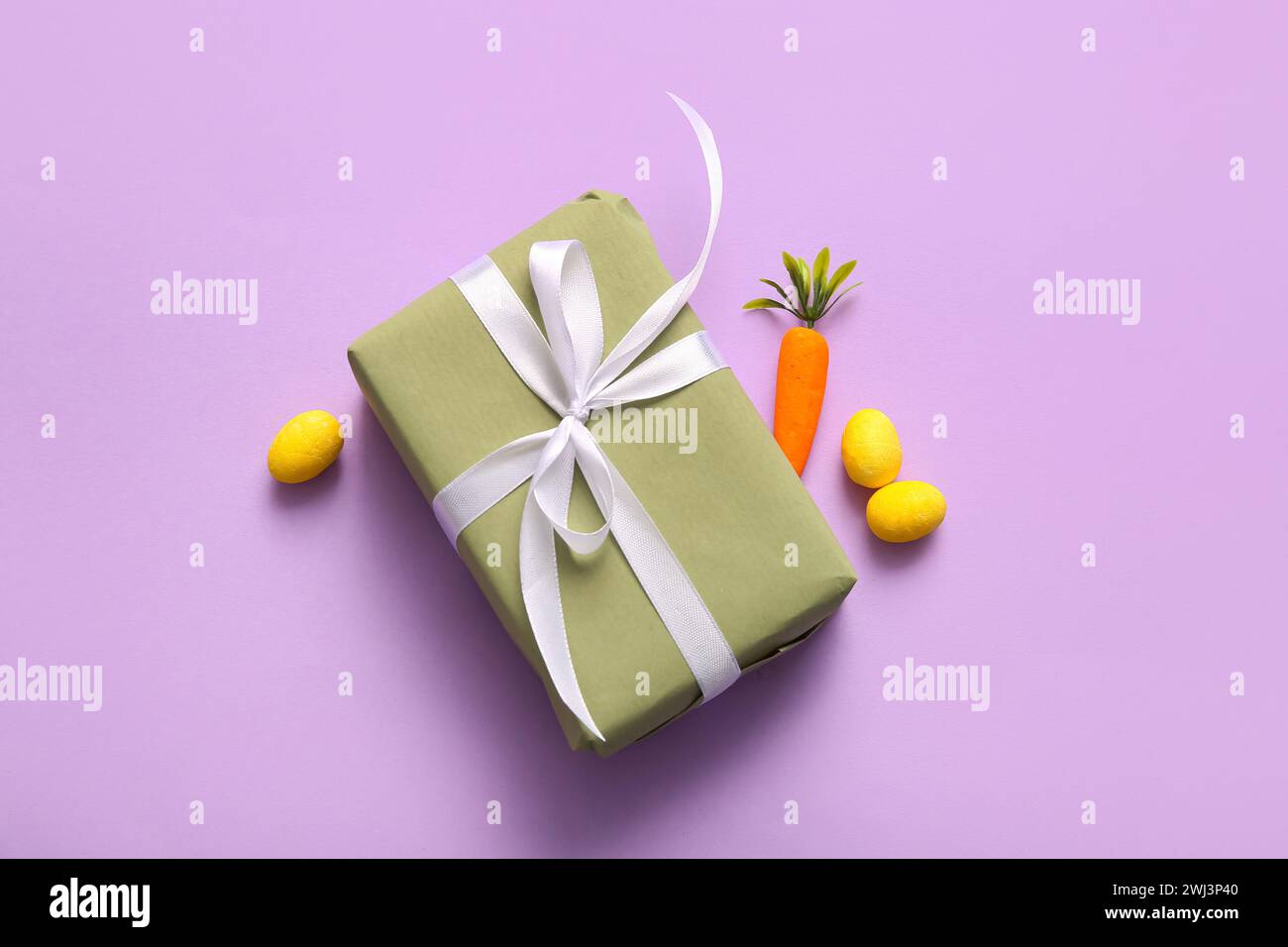 Easter eggs with carrot and gift box on purple background Stock Photo