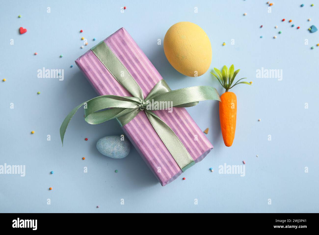 Easter eggs with carrot and gift box on blue background Stock Photo