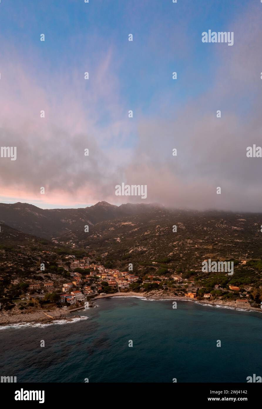 Drone view of Seccheto Beach and village on Elba Island just after sunset with a misty purple sky Stock Photo