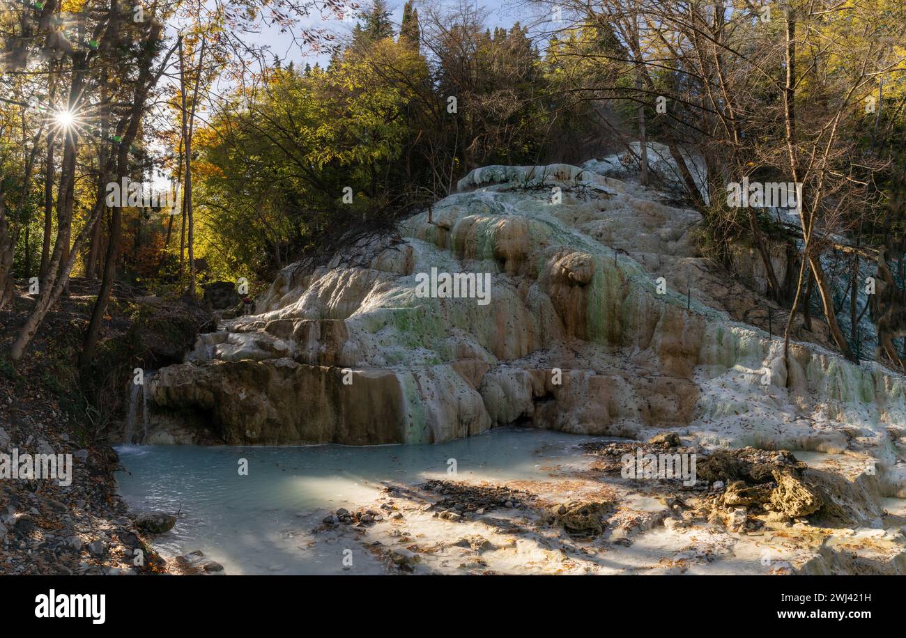 Hot springs thermal baths with turquoise water under fall foliage trees in Bagni San Filippo Stock Photo