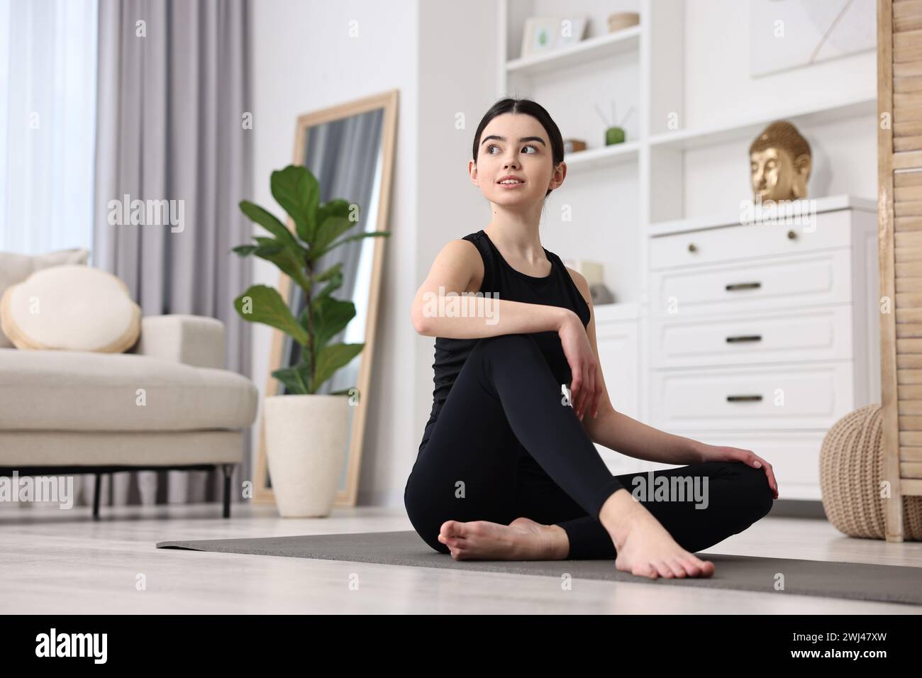 Beautiful girl sitting on yoga mat at home Stock Photo - Alamy