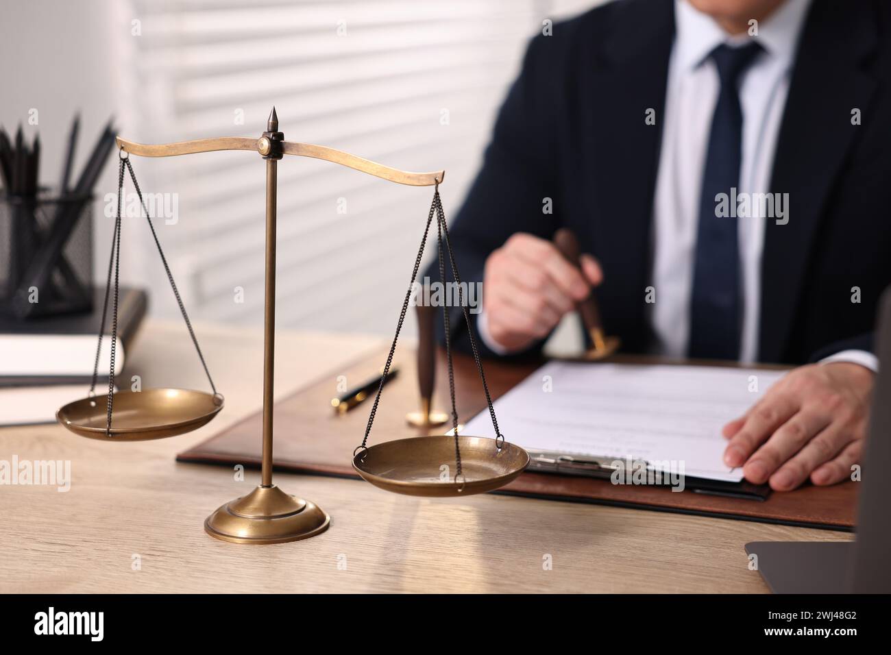 Notary stamping document at wooden table in office, focus on scales of ...
