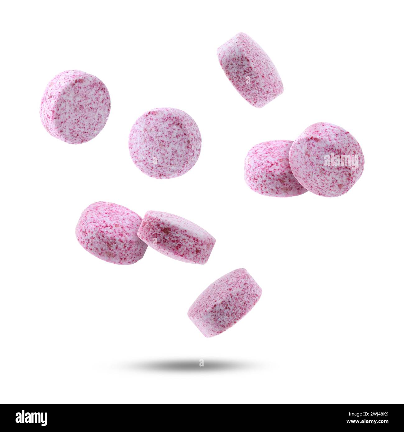 Vitamin. Pink tablets falling on white background Stock Photo - Alamy