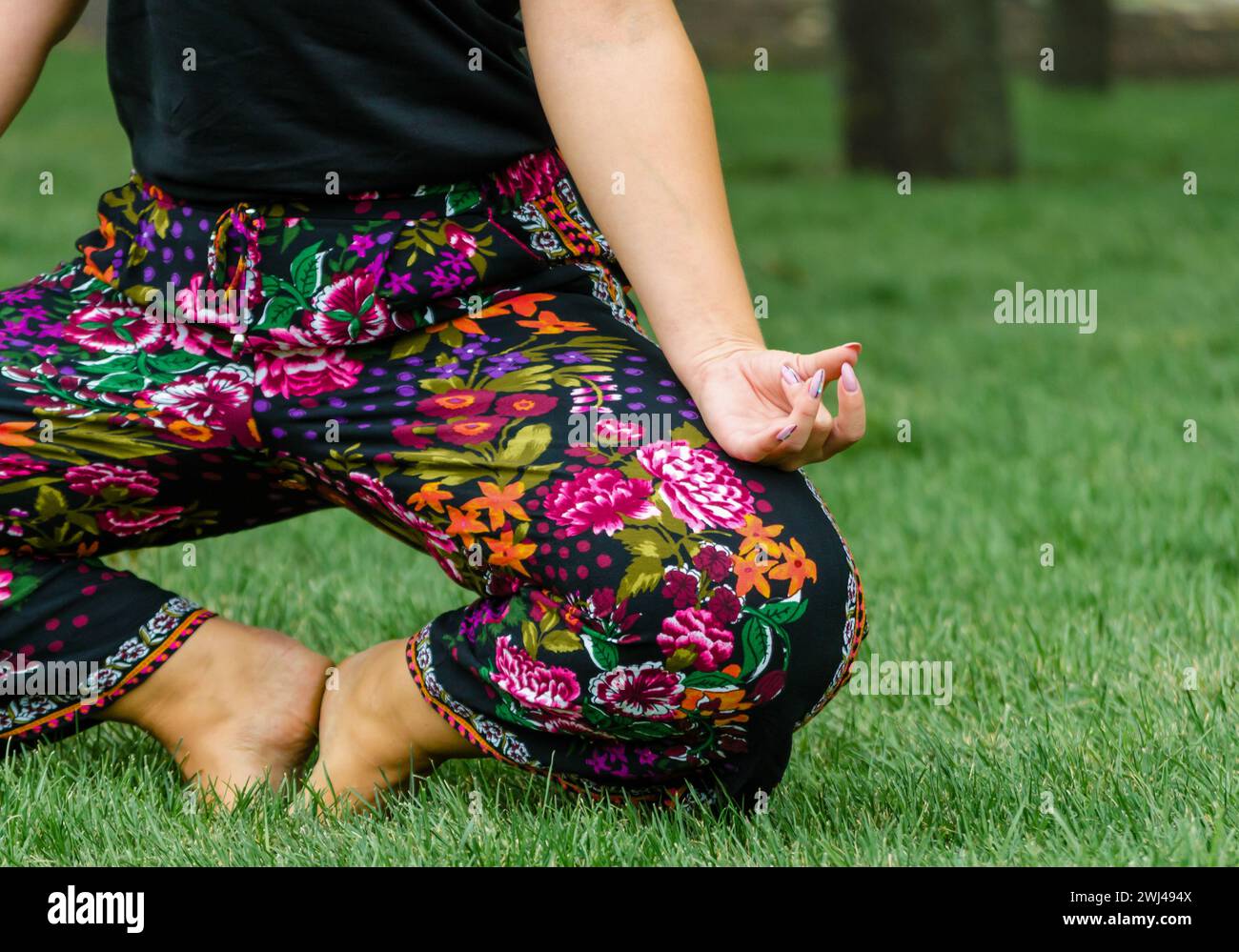 Girls hand in yoga pose on green grass closeup Stock Photo