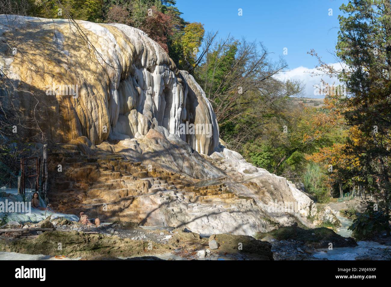People enjoying the hot springs of Bagni San Filippo amidst the calcium carbonate deposits and many pools Stock Photo