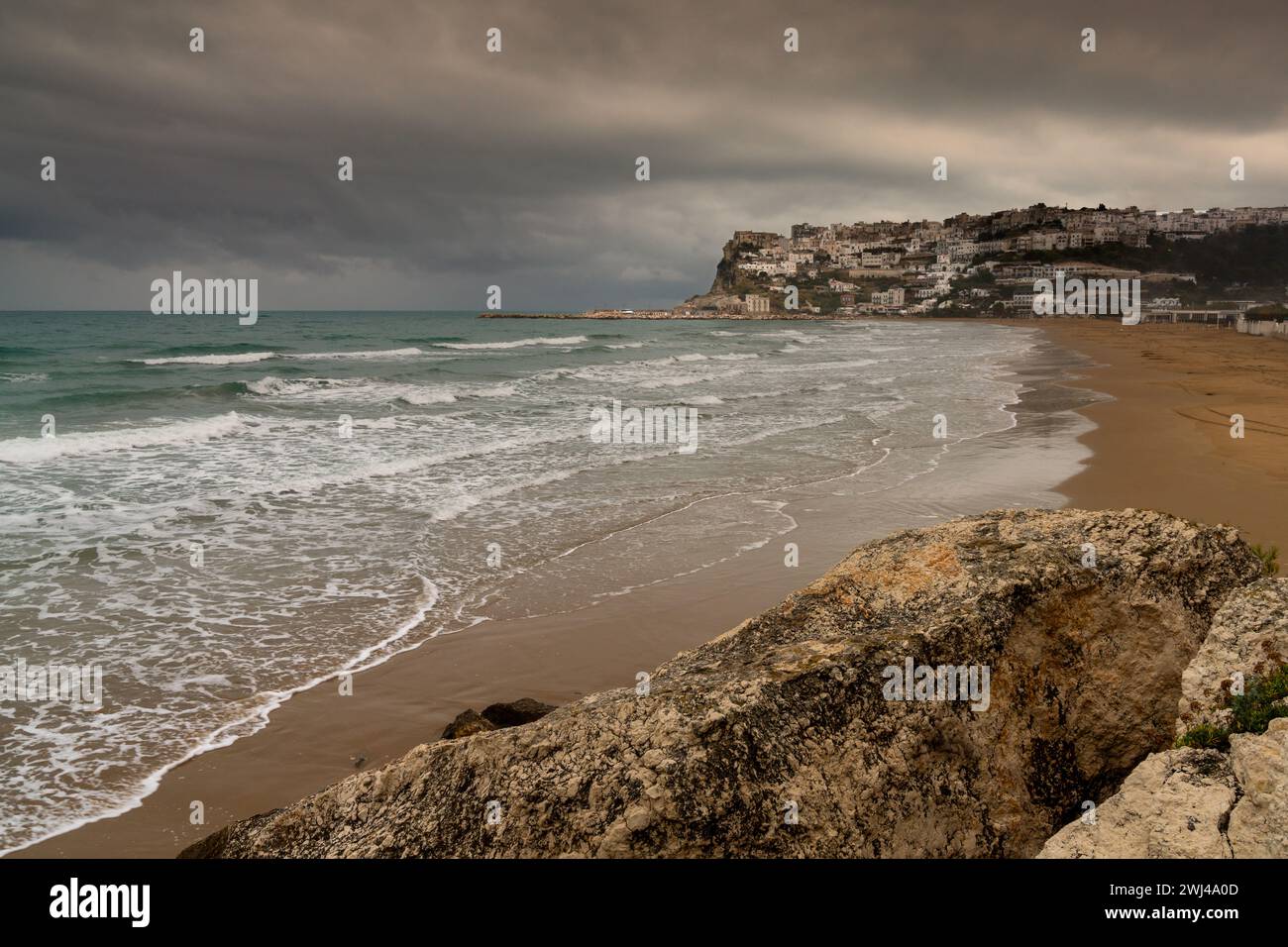 View of Peschici Bay and clifftop town under a rainy and overcast sky Stock Photo